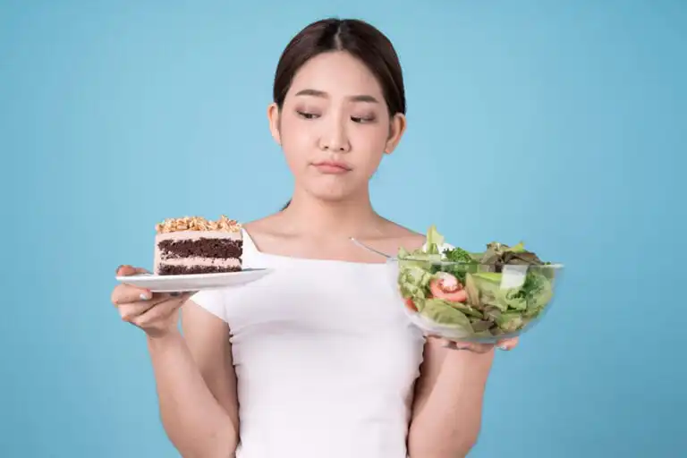 ผู้หญิงชั่งใจระหว่างสลัดเพื่อสุขภาพและเค้ก ซึ่งเป็นอาหารที่ทำให้ตับทำงานหนัก